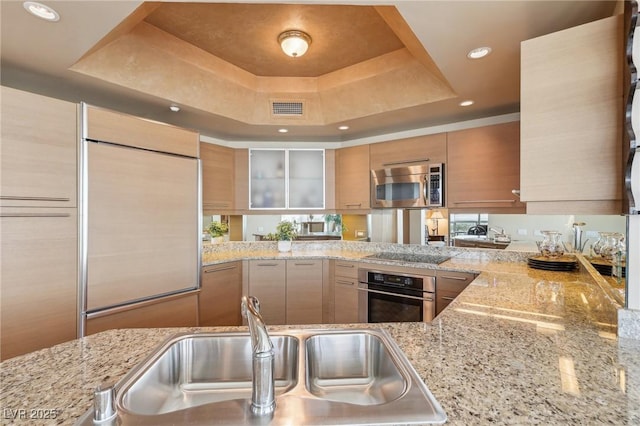 222 Karen Ave Unit 3208, Las Vegas, NV 89109 - kitchen featuring appliances with stainless steel finishes, a tray ceiling, a sink, brown cabinetry, and recessed lighting