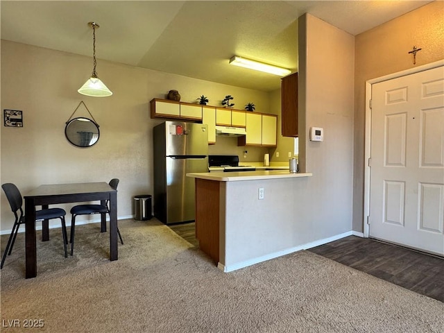 5750 E Hacienda Ave Unit 107, Las Vegas, NV 89122 - kitchen featuring freestanding refrigerator, stove, under cabinet range hood, dark colored carpet, and light countertops