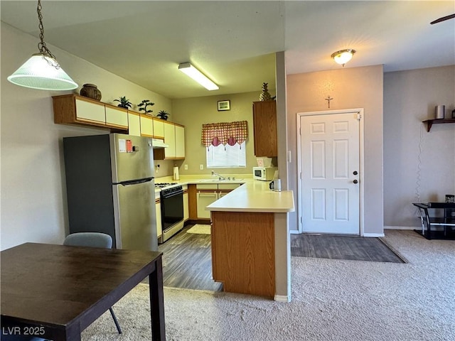 5750 E Hacienda Ave Unit 107, Las Vegas, NV 89122 - kitchen with freestanding refrigerator, gas range oven, a peninsula, light countertops, and carpet
