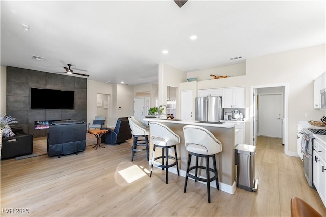 10504 Button Willow Dr, Las Vegas, NV 89134 - kitchen with appliances with stainless steel finishes, a breakfast bar area, light wood finished floors, open floor plan, and recessed lighting