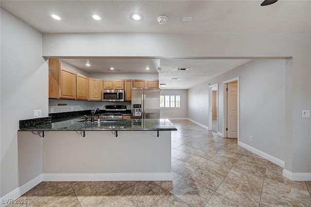 839 Benita Pl, Boulder City, NV 89005 - kitchen with appliances with stainless steel finishes, a peninsula, dark stone countertops, baseboards, and recessed lighting