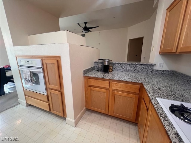 87 E Agate Ave Unit 202, Las Vegas, NV 89123 - kitchen featuring white appliances, a ceiling fan, brown cabinets, light tile patterned floors, and stone counters