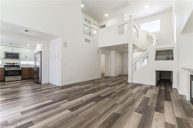 10162 Lemon Thyme St, Las Vegas, NV 89183 - unfurnished living room with a high ceiling, wood finished floors, baseboards, and a glass covered fireplace