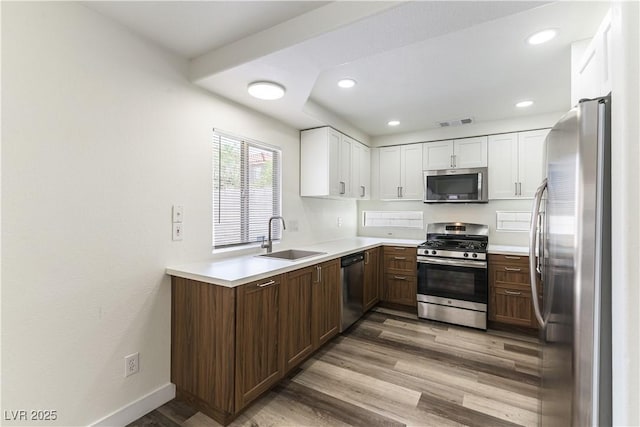 10162 Lemon Thyme St, Las Vegas, NV 89183 - kitchen featuring appliances with stainless steel finishes, a sink, light wood finished floors, white cabinets, and light countertops