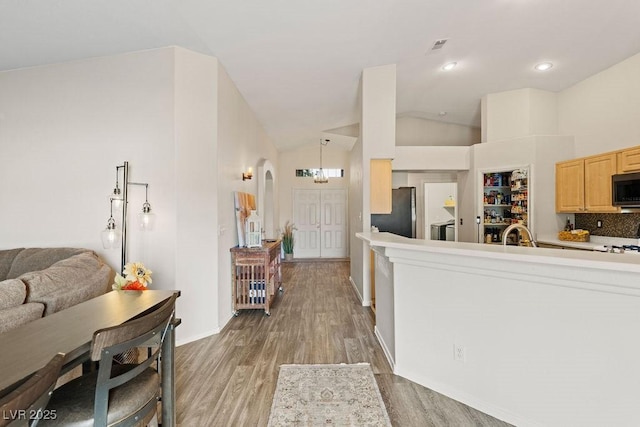 1079 Oak Shade Ln, Henderson, NV 89015 - kitchen featuring black microwave, freestanding refrigerator, light brown cabinets, light wood-type flooring, and vaulted ceiling