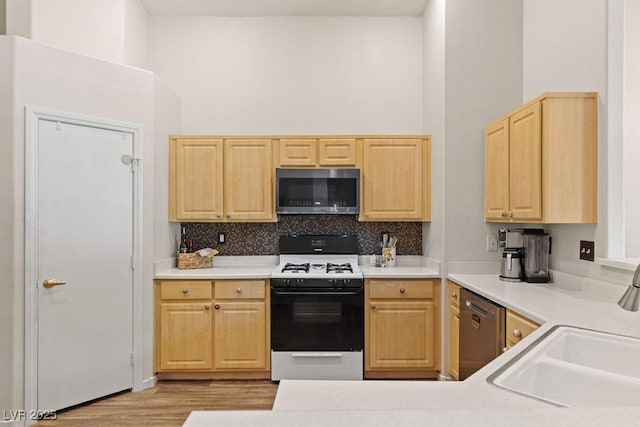 1079 Oak Shade Ln, Henderson, NV 89015 - kitchen with stainless steel appliances, light brown cabinetry, a sink, light wood-type flooring, and decorative backsplash