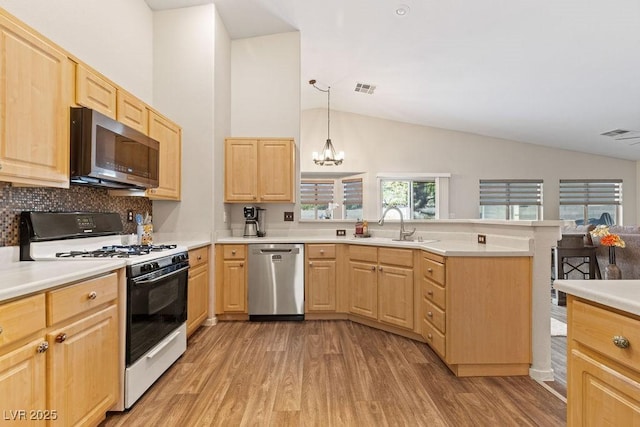 1079 Oak Shade Ln, Henderson, NV 89015 - kitchen with stainless steel appliances, light brown cabinets, vaulted ceiling, and light wood-style flooring
