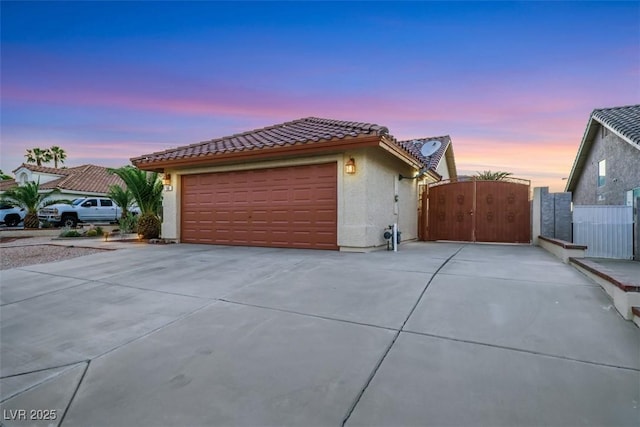 160 Coastal Pier Ct, Henderson, NV 89002 - property exterior at dusk with a gate, a tiled roof, stucco siding, and driveway