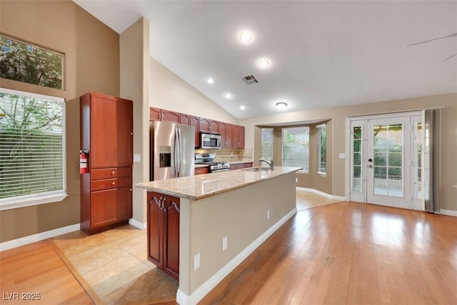 160 Coastal Pier Ct, Henderson, NV 89002 - kitchen with stainless steel appliances, light wood finished floors, an island with sink, light stone countertops, and tasteful backsplash