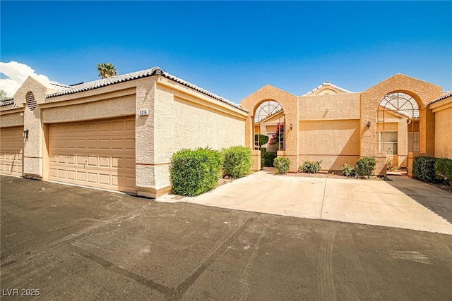 5316 Fieldstone Rd, Las Vegas, NV 89107 - view of front facade with stucco siding, an attached garage, a tiled roof, and asphalt driveway
