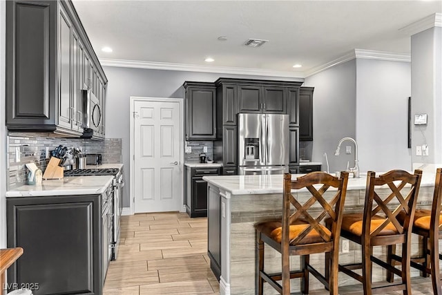 3811 Queen Elizabeth Ct, Laughlin, NV 89029 - kitchen featuring appliances with stainless steel finishes, a kitchen bar, backsplash, crown molding, and light stone countertops