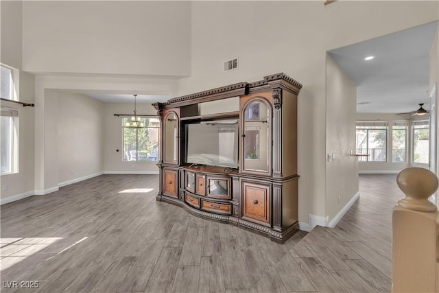 1717 Double Arch Ct, Las Vegas, NV 89128 - unfurnished living room featuring wood finished floors, ceiling fan, a high ceiling, and a chandelier