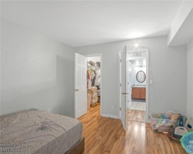 3135 S Mojave Rd Unit 113, Las Vegas, NV 89121 - bedroom featuring wood finished floors, a walk in closet, a closet, and connected bathroom