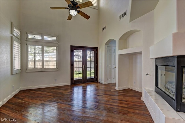 108 Broken Rock Dr, Henderson, NV 89074 - unfurnished living room featuring a fireplace, wood finished floors, a high ceiling, ceiling fan, and french doors