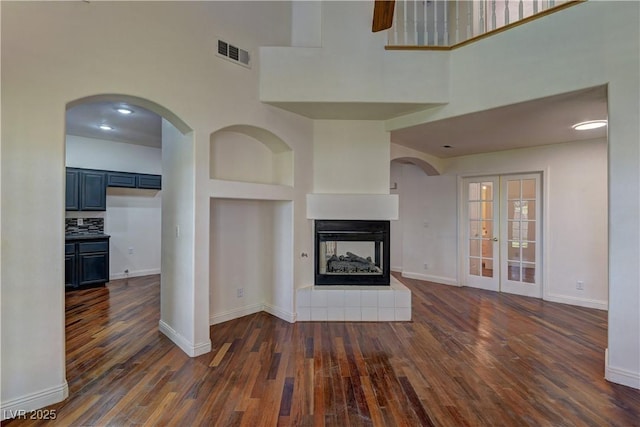 108 Broken Rock Dr, Henderson, NV 89074 - unfurnished living room featuring a towering ceiling, dark wood-style floors, and a multi sided fireplace