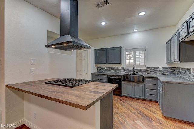 108 Broken Rock Dr, Henderson, NV 89074 - kitchen featuring black dishwasher, wall chimney range hood, butcher block counters, cooktop, and a peninsula