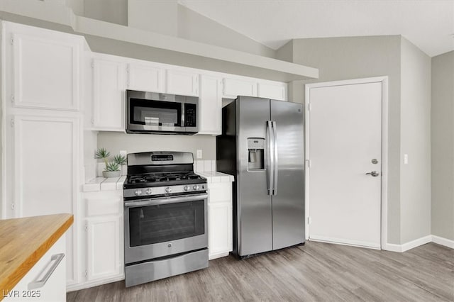 3053 Anchor Chain Dr, Las Vegas, NV 89128 - kitchen with appliances with stainless steel finishes, tile counters, light wood-style flooring, and white cabinetry
