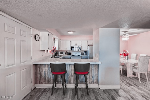 2725 S Nellis Blvd Unit 1038, Las Vegas, NV 89121 - kitchen featuring white appliances, tile counters, a textured ceiling, dark wood-style flooring, and white cabinets
