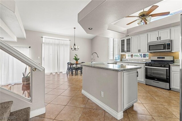 2080 Silver Breeze Ave, Las Vegas, NV 89183 - kitchen with stainless steel appliances, a sink, light tile patterned floors, white cabinetry, and glass insert cabinets