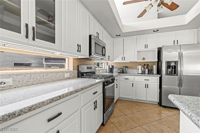 2080 Silver Breeze Ave, Las Vegas, NV 89183 - kitchen with stainless steel appliances, white cabinets, ceiling fan, backsplash, and light tile patterned flooring