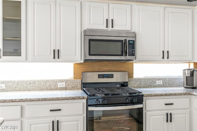 2080 Silver Breeze Ave, Las Vegas, NV 89183 - kitchen with appliances with stainless steel finishes, white cabinetry, glass insert cabinets, and tasteful backsplash