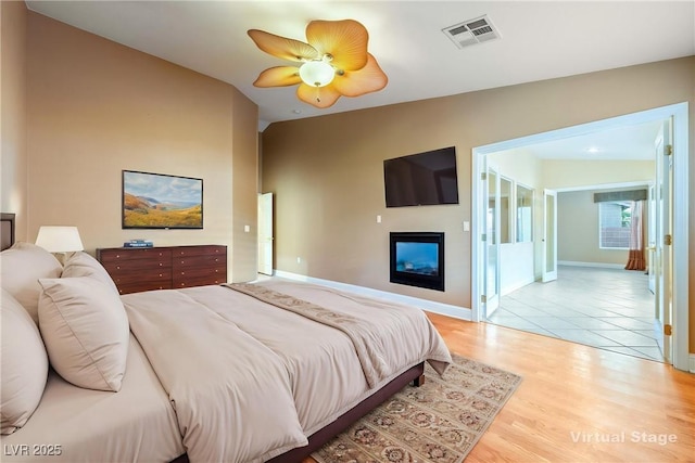 11082 Sospel Pl, Las Vegas, NV 89141 - bedroom with a glass covered fireplace, baseboards, light wood-style floors, lofted ceiling, and ceiling fan