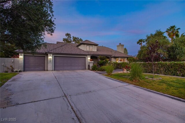 2222 Lucerne Ct, Henderson, NV 89014 - view of front of home with an attached garage, concrete driveway, a chimney, stucco siding, and a front lawn