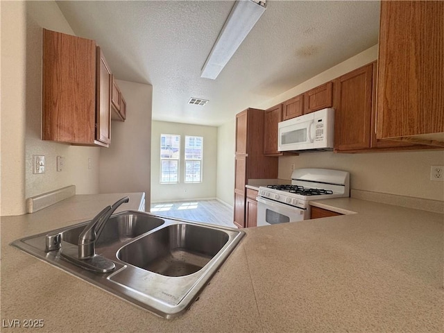 7469 Margollini St, Las Vegas, NV 89148 - kitchen featuring white appliances, a sink, a textured ceiling, brown cabinets, and light countertops