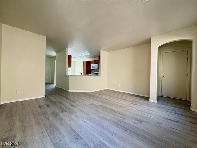 7469 Margollini St, Las Vegas, NV 89148 - unfurnished living room featuring wood finished floors, baseboards, and arched walkways