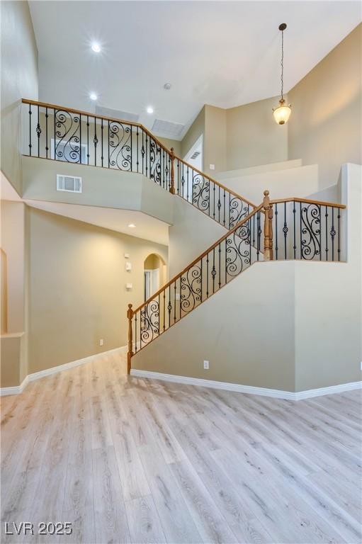 11478 Bargetto Ct, Las Vegas, NV 89141 - unfurnished living room featuring a towering ceiling, wood finished floors, recessed lighting, baseboards, and arched walkways