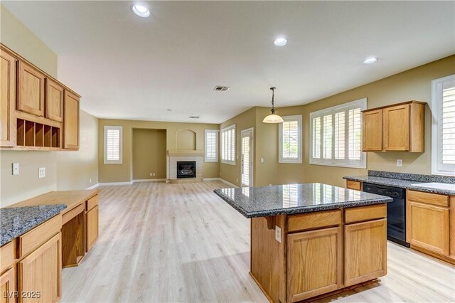 11478 Bargetto Ct, Las Vegas, NV 89141 - kitchen featuring dishwasher, light wood-type flooring, a center island, a fireplace, and dark stone countertops