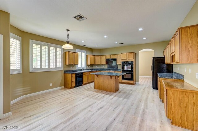 11478 Bargetto Ct, Las Vegas, NV 89141 - kitchen with black appliances, arched walkways, a center island, baseboards, and a kitchen breakfast bar