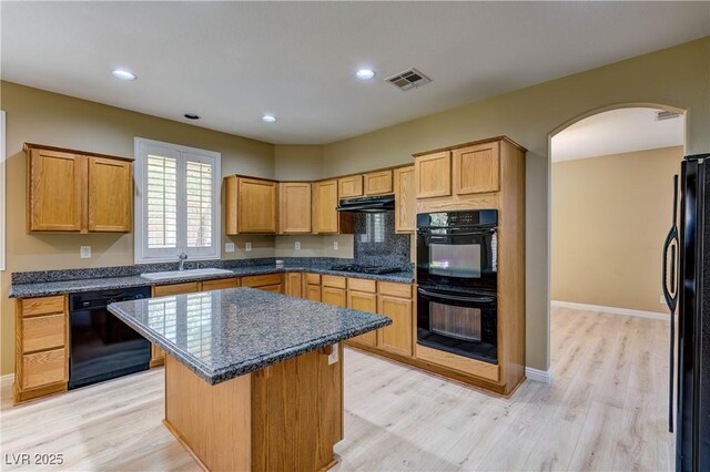 11478 Bargetto Ct, Las Vegas, NV 89141 - kitchen with black appliances, exhaust hood, arched walkways, a sink, and light wood finished floors