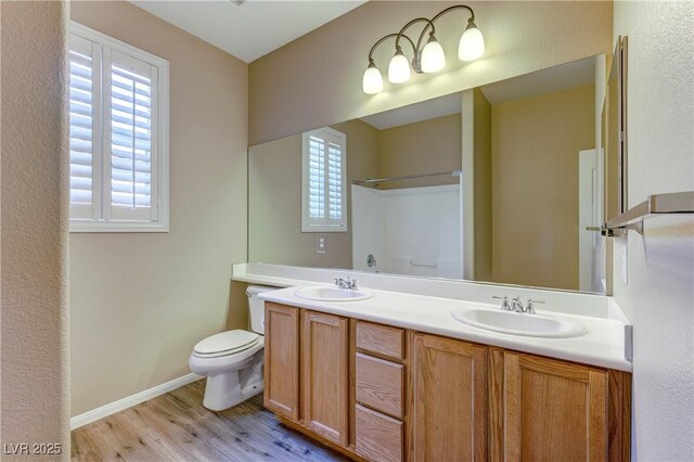 11478 Bargetto Ct, Las Vegas, NV 89141 - full bathroom featuring wood finished floors, double vanity, toilet, a shower, and baseboards