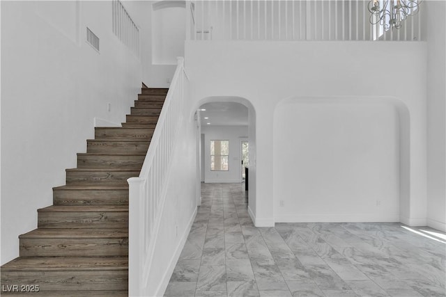 4016 Owlshead Mountain St, Las Vegas, NV 89129 - staircase with marble finish flooring, a high ceiling, arched walkways, a chandelier, and baseboards