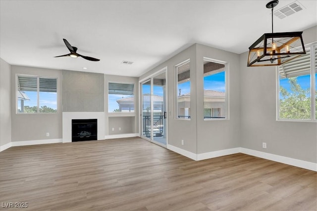 9116 Vista Greens Way Unit 104, Las Vegas, NV 89134 - unfurnished living room featuring baseboards, a chandelier, light wood finished floors, ceiling fan, and a large fireplace