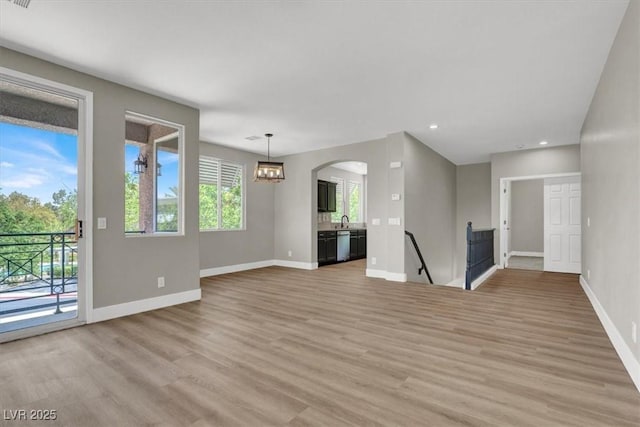 9116 Vista Greens Way Unit 104, Las Vegas, NV 89134 - unfurnished living room with light wood-type flooring, baseboards, recessed lighting, a sink, and arched walkways