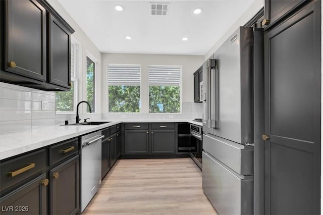 9116 Vista Greens Way Unit 104, Las Vegas, NV 89134 - kitchen featuring appliances with stainless steel finishes, light wood-style flooring, recessed lighting, decorative backsplash, and a sink