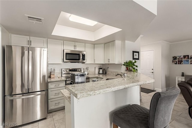 8600 W Charleston Blvd Unit 2187, Las Vegas, NV 89117 - kitchen featuring appliances with stainless steel finishes, a peninsula, a kitchen breakfast bar, and light stone countertops