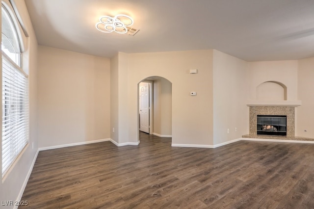 8737 Red Brook Dr Unit 204, Las Vegas, NV 89128 - unfurnished living room featuring arched walkways, dark wood-style floors, baseboards, and a fireplace