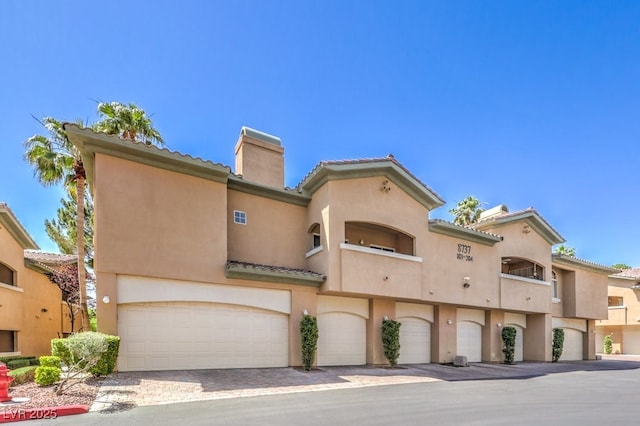 8737 Red Brook Dr Unit 204, Las Vegas, NV 89128 - view of front of property with a chimney, stucco siding, an attached garage, and a tiled roof