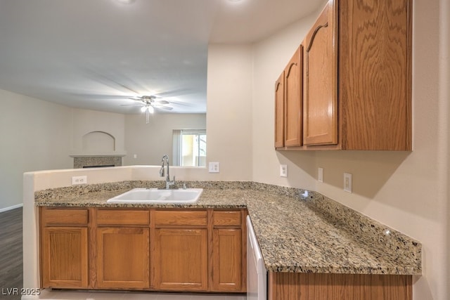 8737 Red Brook Dr Unit 204, Las Vegas, NV 89128 - kitchen with a sink, a peninsula, a ceiling fan, brown cabinets, and light stone countertops