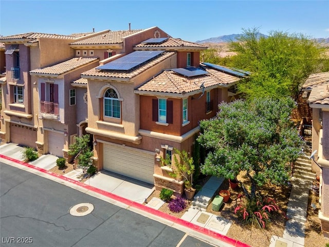 9975 Sand Key St, Las Vegas, NV 89178 - view of front of home featuring a garage, a tiled roof, roof mounted solar panels, and stucco siding