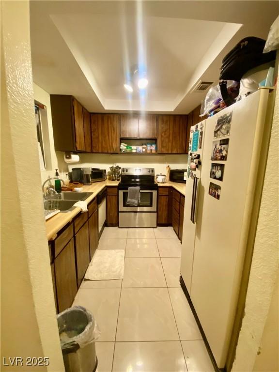 1748 Jupiter Ct Unit C, Las Vegas, NV 89119 - kitchen with electric stove, freestanding refrigerator, a raised ceiling, light countertops, and a sink