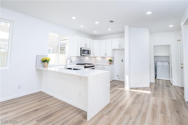 669 Elliot Peak Ave, Las Vegas, NV 89183 - kitchen with appliances with stainless steel finishes, washer / dryer, a sink, a peninsula, and light countertops