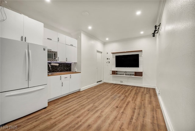 5553 Coral Gate St, Las Vegas, NV 89148 - kitchen with freestanding refrigerator, light wood-style flooring, baseboards, stainless steel microwave, and white cabinetry