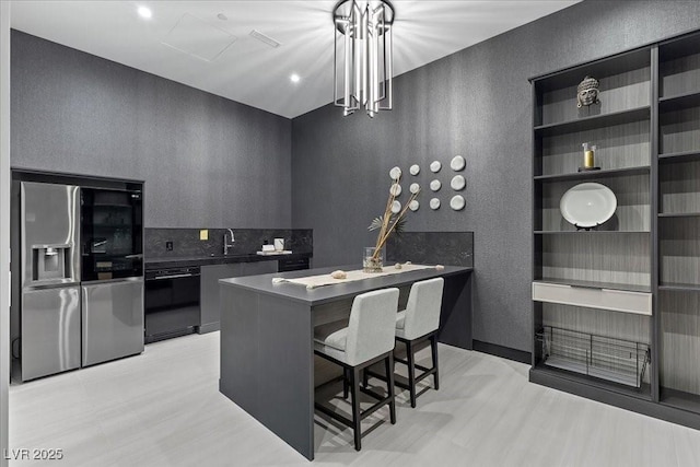 38 Skybird Ct, Las Vegas, NV 89135 - kitchen featuring stainless steel fridge, dishwasher, a textured wall, a sink, and a breakfast bar
