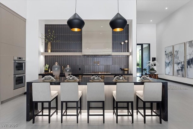 38 Skybird Ct, Las Vegas, NV 89135 - kitchen with modern cabinets, double oven, a breakfast bar, a high ceiling, and dark countertops