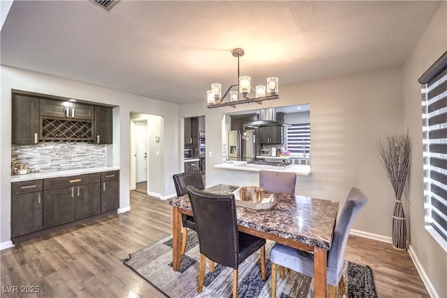 8932 Beach Front Dr, Las Vegas, NV 89117 - dining space with a chandelier, wood finished floors, baseboards, and bar area