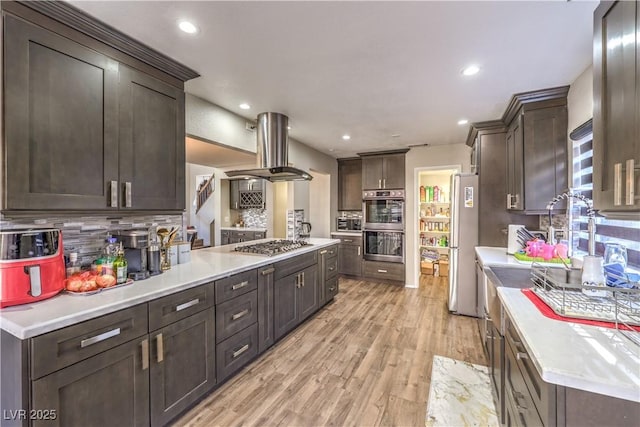 8932 Beach Front Dr, Las Vegas, NV 89117 - kitchen with island exhaust hood, dark brown cabinetry, stainless steel appliances, backsplash, and recessed lighting